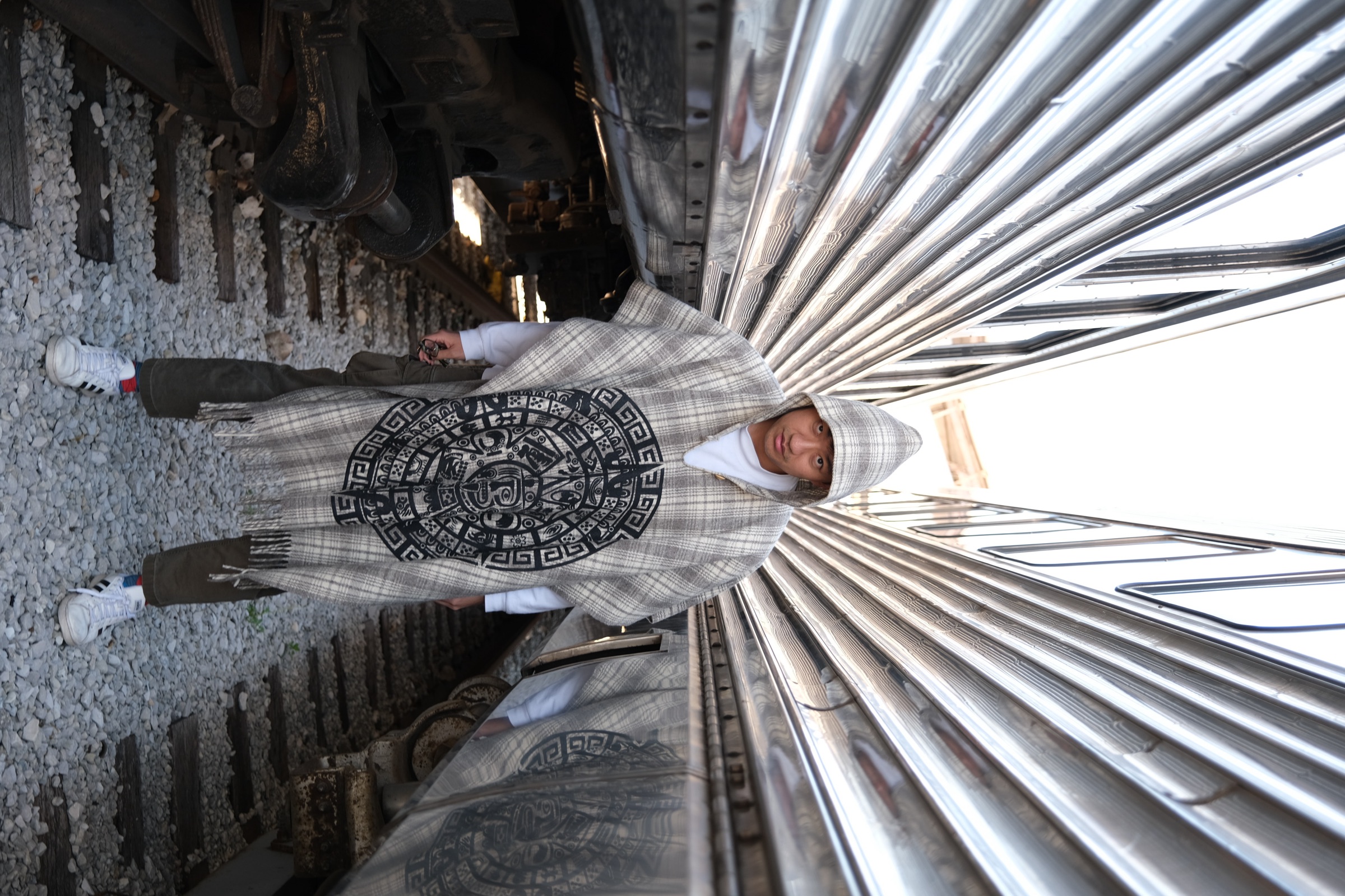 Xiaoyu Liu standing between reflective train cars